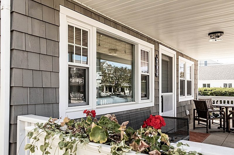 Energy-efficient white vinyl windows with a combination of double-hung and picture window designs, installed on a modern house with gray siding