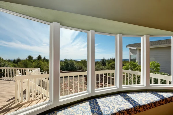 Windows with white frames, offering panoramic views of the ocean and surrounding landscape, enhancing natural light in the cozy seating area