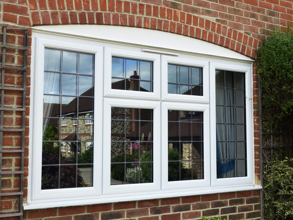 High-quality white window with decorative grid pattern, installed on a brick wall, offering energy efficiency and enhanced aesthetics