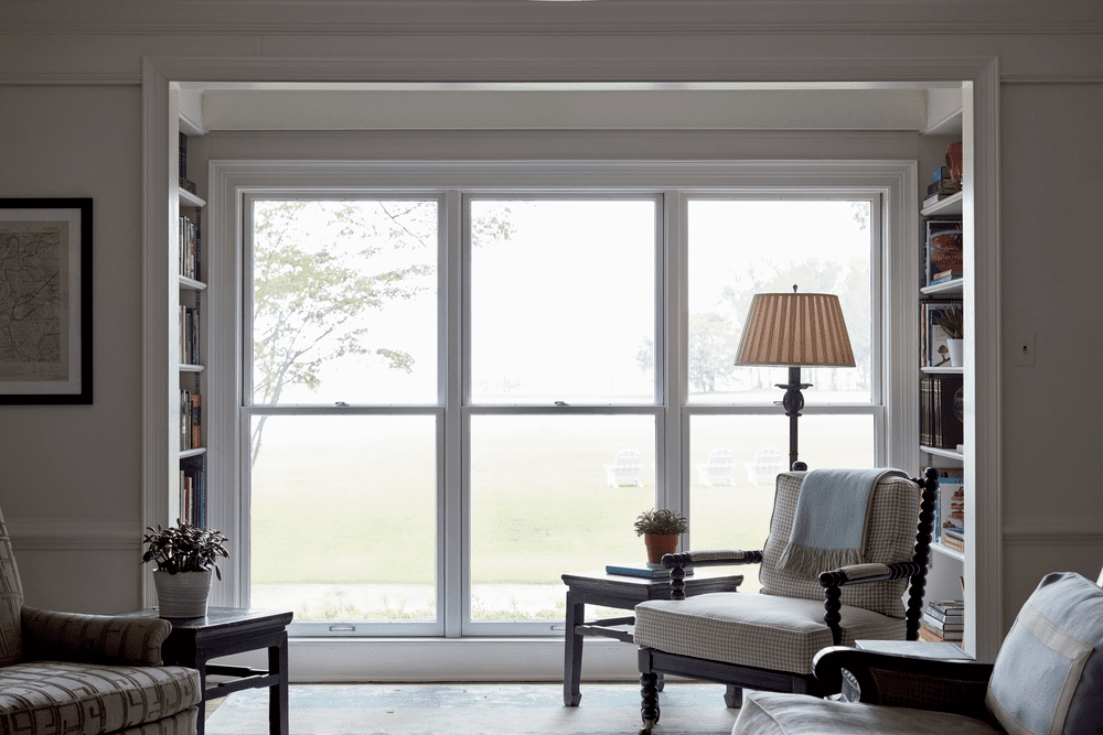 Large double-hung window in a cozy living room with classic furniture and natural light enhancing the space