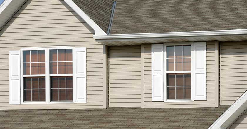 Exterior of a house with two white double-hung windows, framed by white shutters