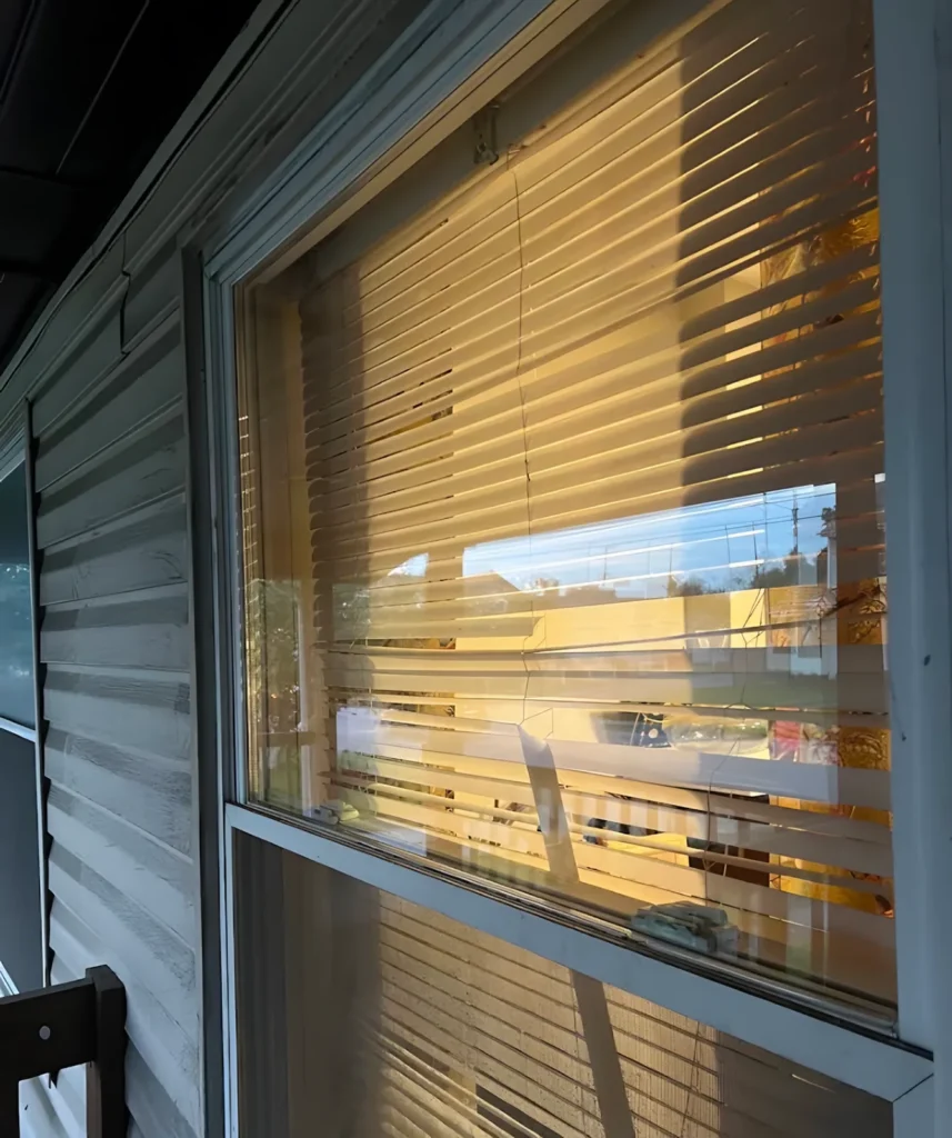 Evening light through horizontal blinds with a crack running down the window glass