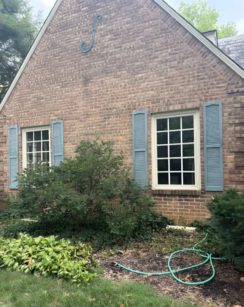 Brick gable of a house with blue shutters and two divided-light windows